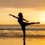 silhouette of woman standing on seashore during sunset