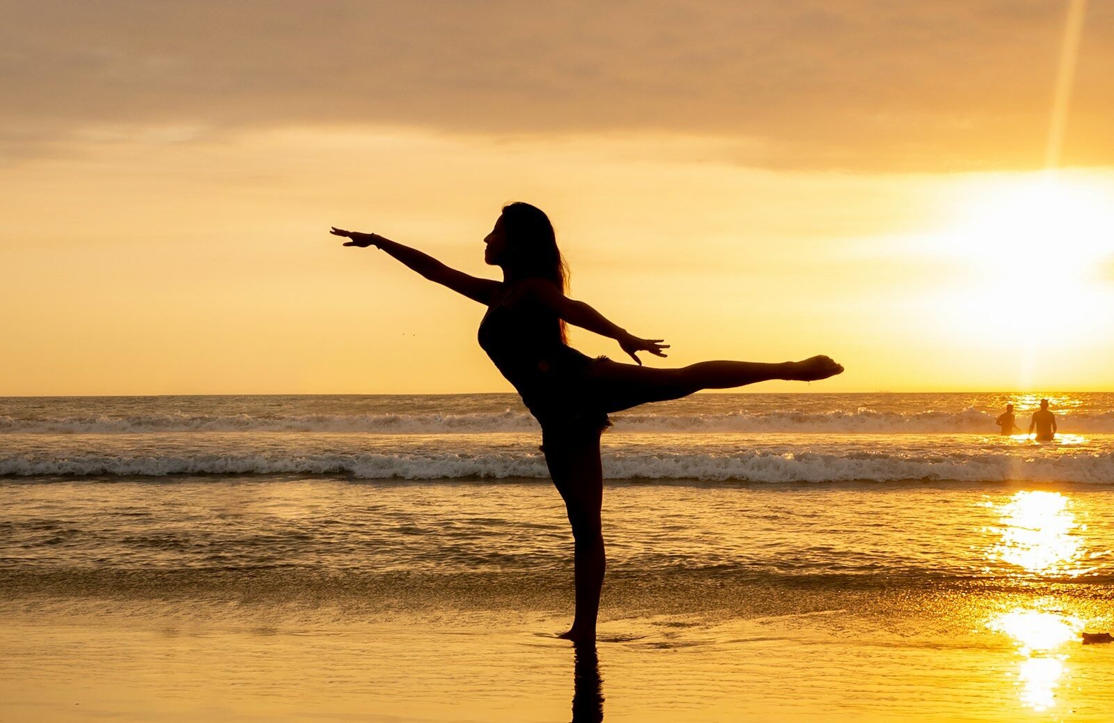 silhouette of woman standing on seashore during sunset