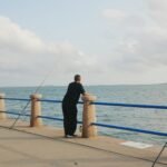 Man fishing on a pier overlooking the ocean.