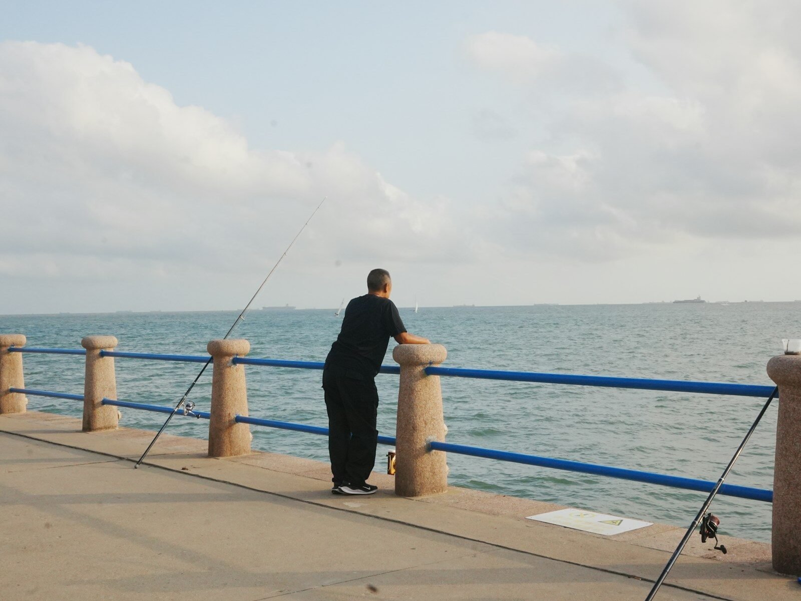 Man fishing on a pier overlooking the ocean.